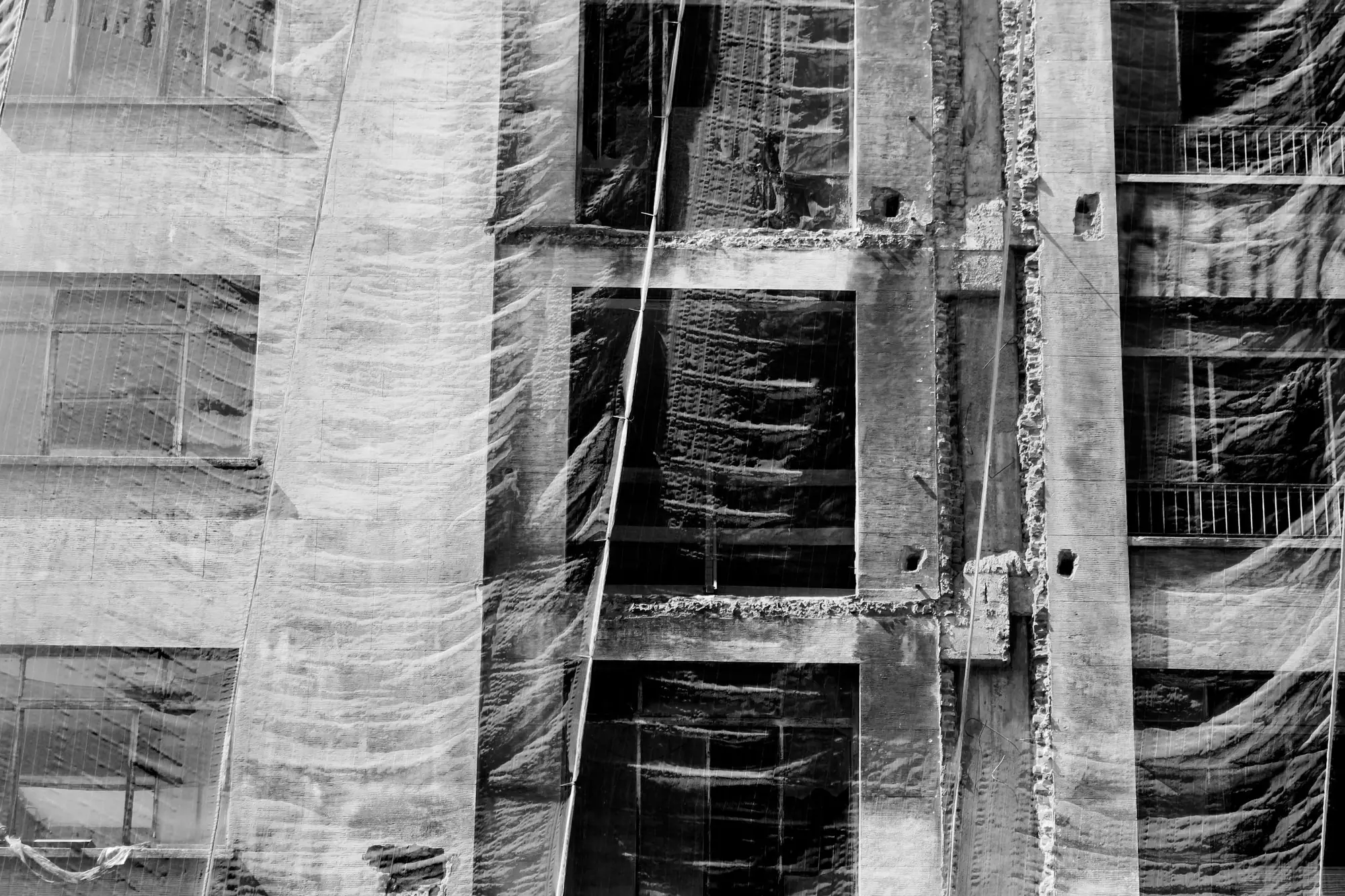 Fine protective netting stretched over a building under renovation, its floors visible behind.