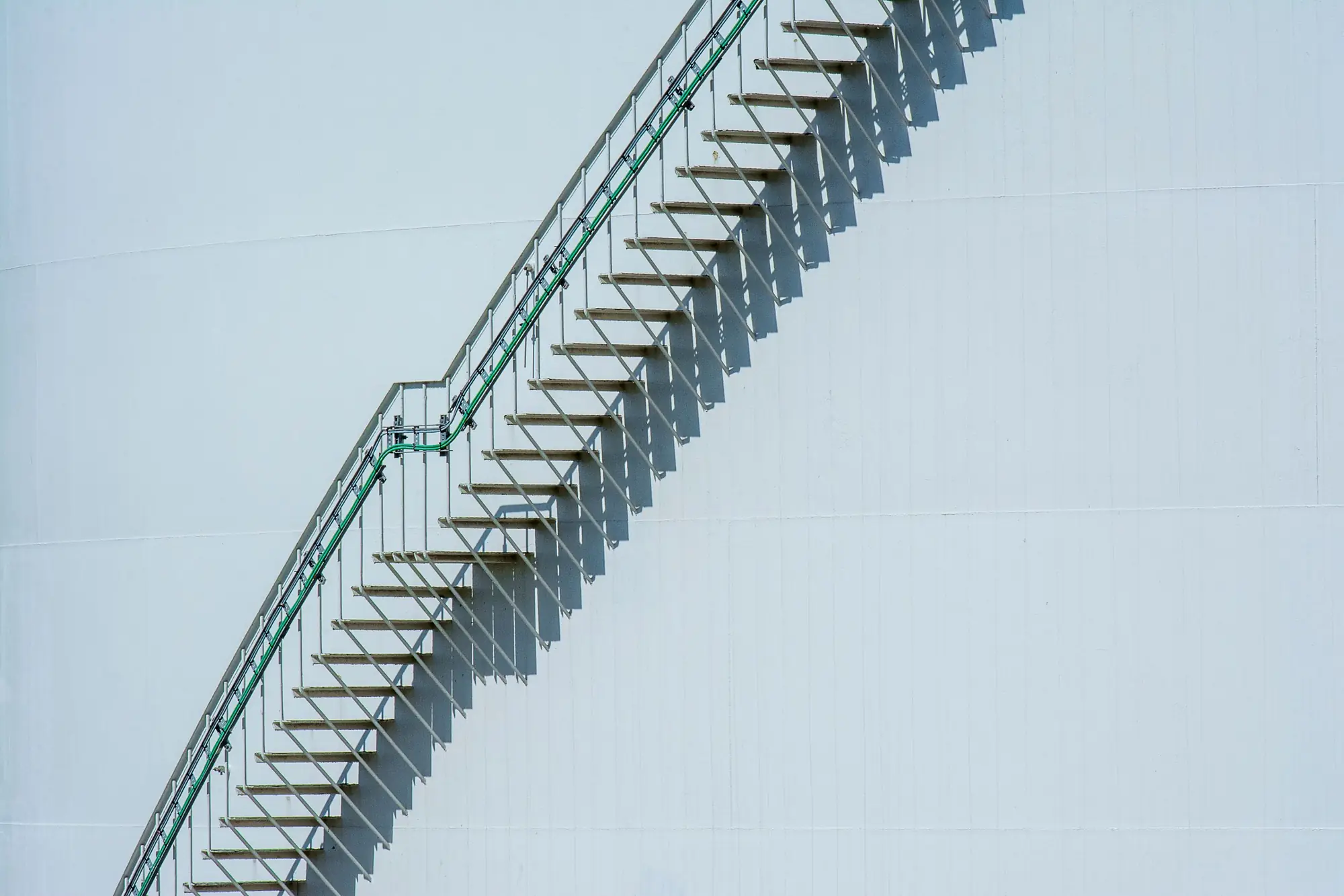 An external metal staircase climbing a plain white wall in regular flights.
